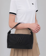 Model wearing ANEW black shoulder bag with white polo and pleated skirt, golf lifestyle styling